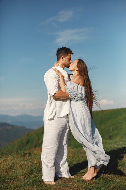 Mann und Frau in den Bergen. Junges Paar verliebt in Sonnenuntergang. Frau in einem blauen Kleid.