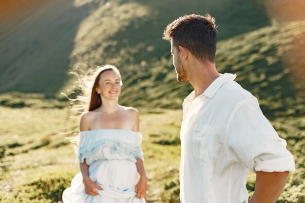 Mann und Frau in den Bergen. Junges Paar verliebt in Sonnenuntergang. Frau in einem blauen Kleid.