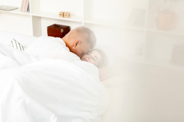 Mann und Frau kuscheln sich hinter die Bettdecke