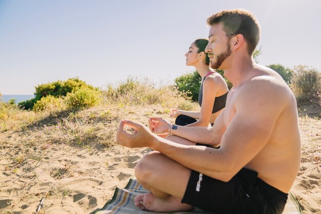 Mann und Frau meditieren am Strand