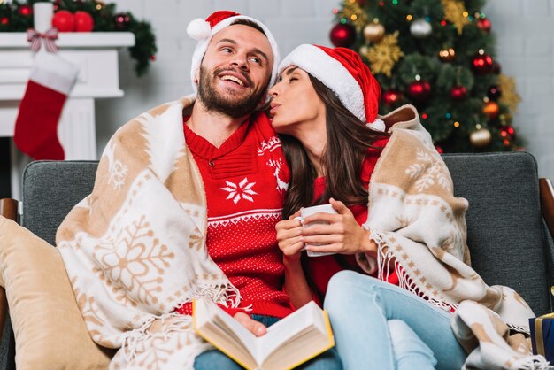 Mann und Frau mit Cup und Buch auf Sofa