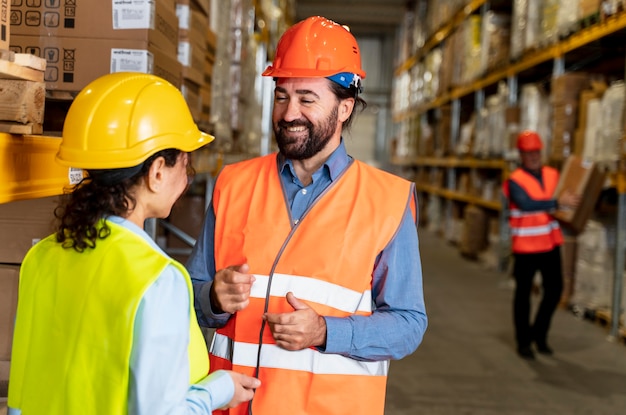 Mann und Frau mit Helm, der im Lager arbeitet