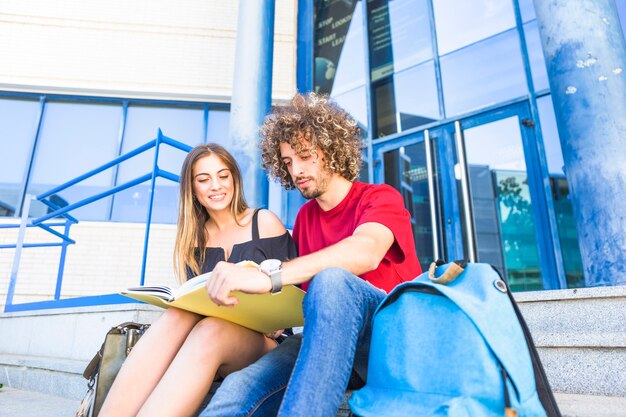 Mann und Frau mit Lehrbuch nahe Universität