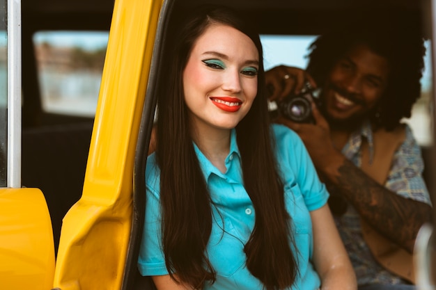 Mann und Frau posieren im Retro-Stil mit Auto und Kamera