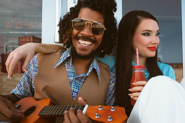 Mann und Frau posieren zusammen im Retro-Stil mit Ukulele und Getränk