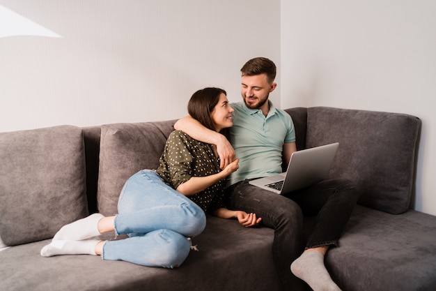 Mann und Frau sitzen auf Sofa mit einem Laptop