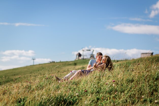 Mann und Frau sitzen, umarmend auf dem Gras vor schöner Landschaft