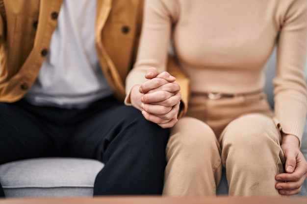 Mann und Frau sitzen zu Hause mit den Händen zusammen auf dem Sofa