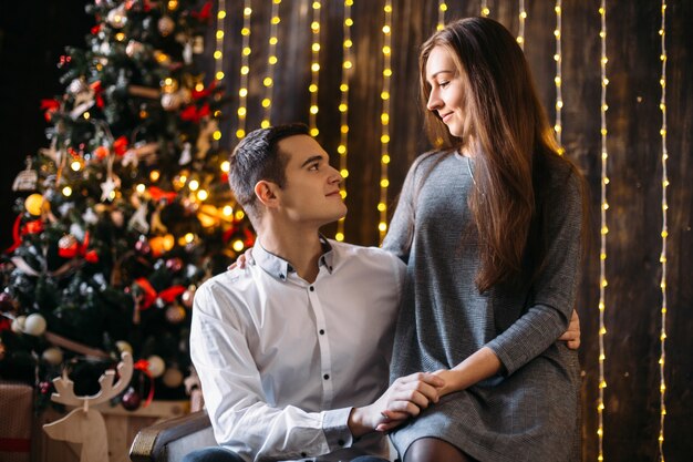 Mann und Frau stehen vor einem Weihnachtsbaum in einem gemütlichen Zimmer