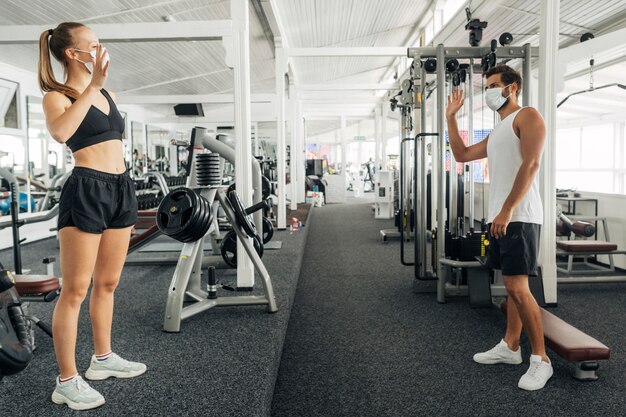 Mann und Frau winken einander im Fitnessstudio zu