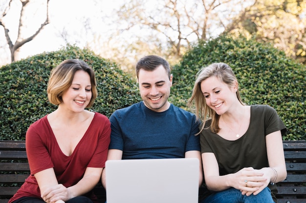 Mann und Frauen, die Laptop im Park verwenden