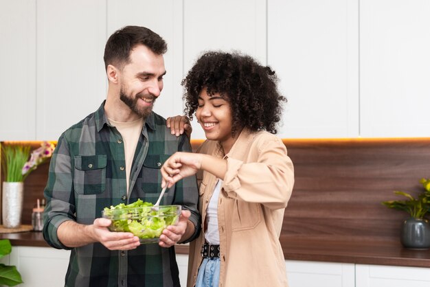 Mann und schöne Frau, die geschmackvollen Salat versuchen