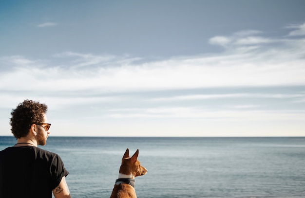 Kostenloses Foto mann und sein hund am strand bewundern das meer