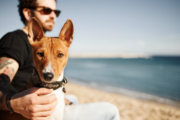 Mann und sein Hund am Strand bewundern das Meer