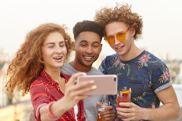 Mann und seine zwei Freunde mit lockigem Haar machen Selfies