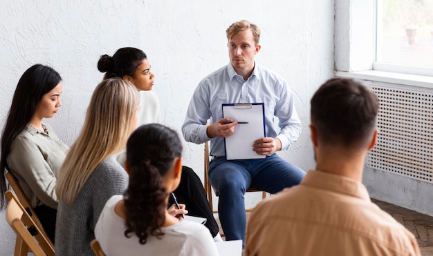 Mann zeigt Zwischenablage bei einer Gruppentherapiesitzung