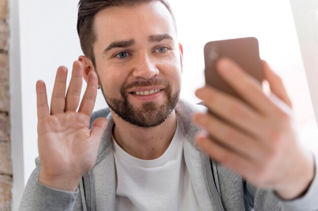 Mann zu Hause mit Videoanruf mit Familie