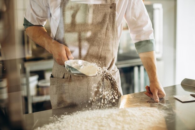 Mannbäcker, der Mehl verwendet, um Teig zum Backen vorzubereiten