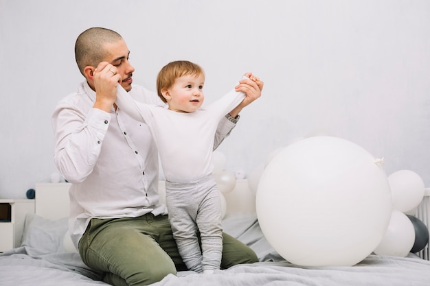 Mannhändchenhalten des kleinen Babys auf Bett