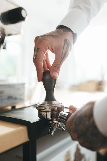 Mannhände arbeiten mit Kaffeemaschine im Restaurant. Schließen Sie herauf Baristahände, die das Kaffeekochen im Café vorbereiten