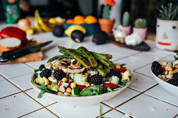 Mannhände, die großen tiefen Teller voll des gesunden paläo-vegetarischen Salats halten, der aus frischen biologischen biologischen Bestandteilen, Gemüse und Früchten, Beeren und anderen ernährungsphysiologischen Dingen hergestellt wird