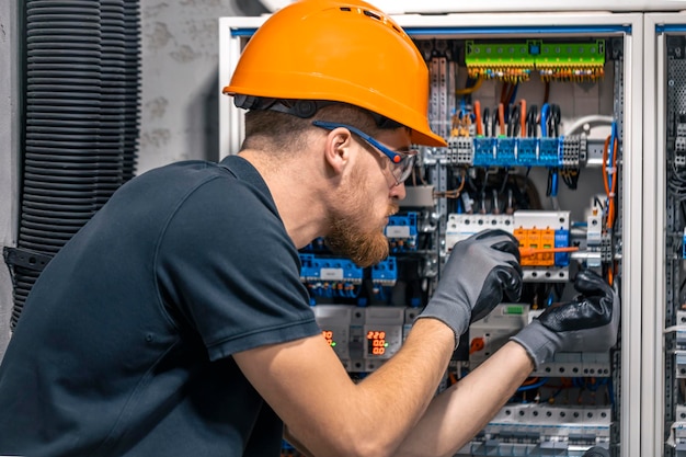 Kostenloses Foto mannlicher elektriker arbeitet an einer schalttafel mit sicherungen