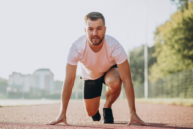 Mannsportler, der morgens im Stadion joggt