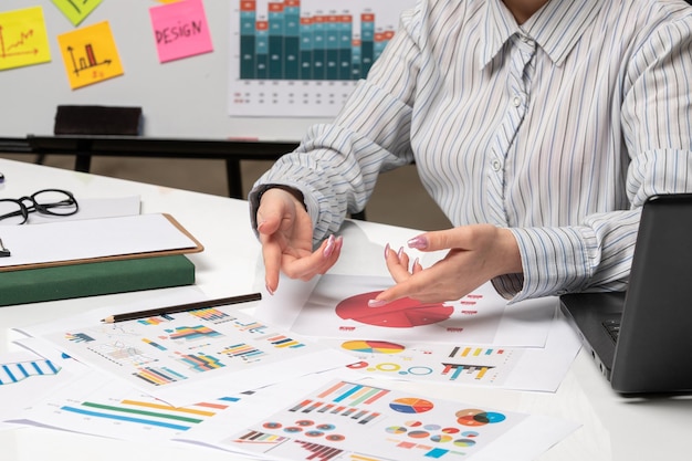 Marketing-Geschäftsfrau im grauen Blazer im Büro mit Computer, der auf Diagramme zeigt