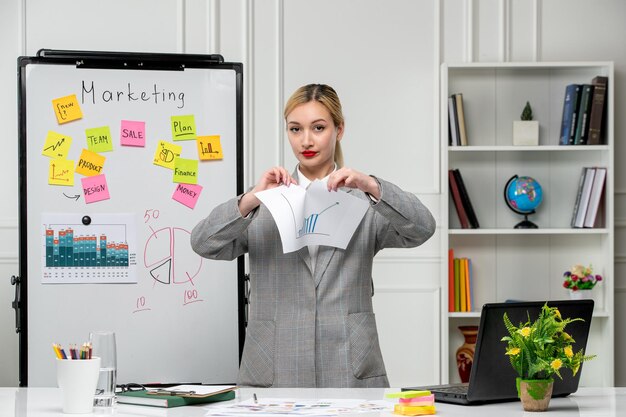 Marketing junge hübsche nette Geschäftsfrau im grauen Blazer im Büro, das Statistikdiagramm zerreißt