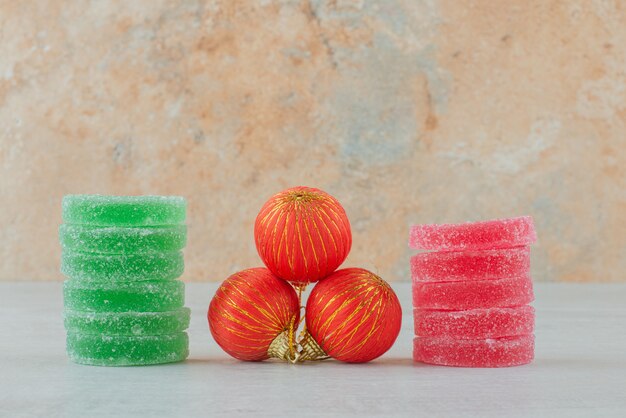 Marmelade aus grünem und rotem Zucker mit roten Weihnachtskugeln auf Marmorhintergrund. Hochwertiges Foto