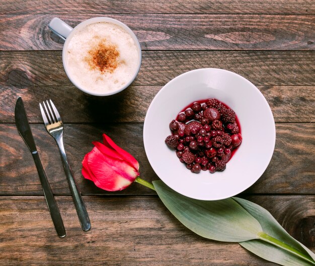 Marmelade in Schüssel, frische Blumen, Besteck und Tasse Getränk