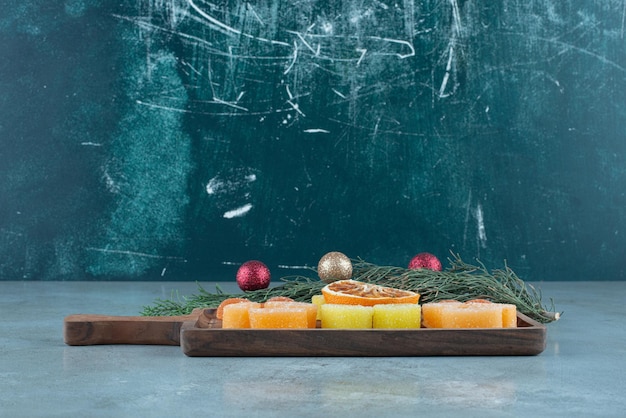 Marmeladen und eine Scheibe getrocknete Orange auf einem Tablett neben einer kleinen Girlande auf Marmor.