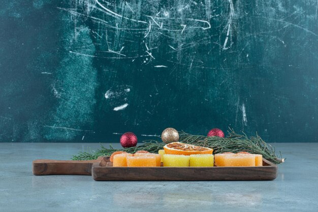 Marmeladen und eine Scheibe getrocknete Orange auf einem Tablett neben einer kleinen Girlande auf Marmor.