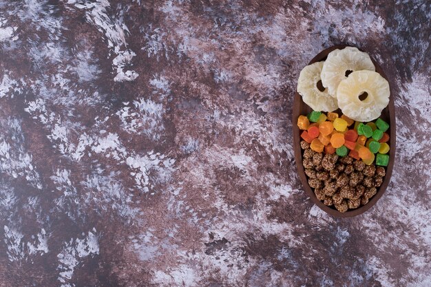 Marmeladen und trocken geschnittene Früchte in einer Holzplatte auf dem Marmortisch