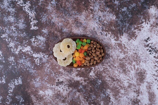 Marmeladen und trocken geschnittene Früchte in einer Holzplatte auf dem Marmortisch