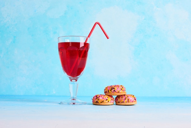 Marshmallow-Kekse mit einem Glas Saft auf blauem Hintergrund, in der Mitte.