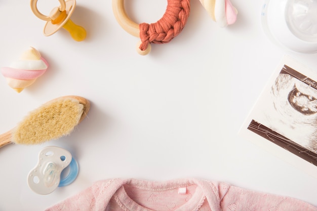 Marshmallow; rosa Baby-Strampelanzug; Bürste; Schnuller; Milchflasche und Spielzeug auf weißem Hintergrund