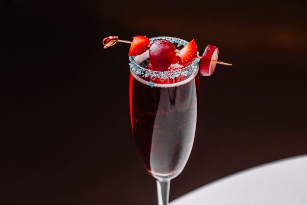 Martini-Cocktail von der Seite mit Erdbeere und Traube im Champagnerglas