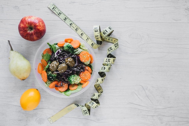 Maßband in der Nähe von Salat und Früchten