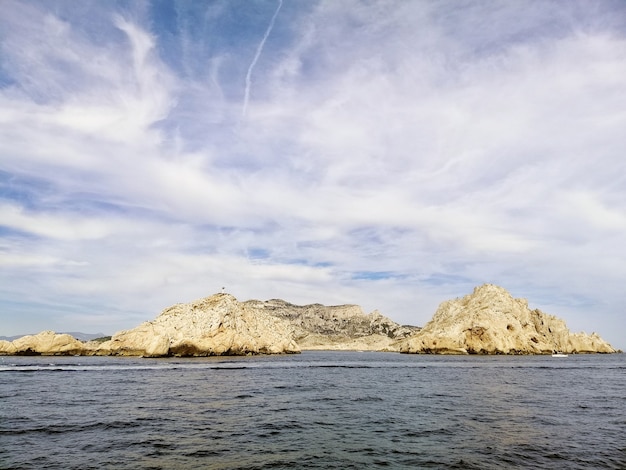 Massif des Calanques, umgeben vom Meer unter bewölktem Himmel und Sonnenlicht in Marseille in Frankreich