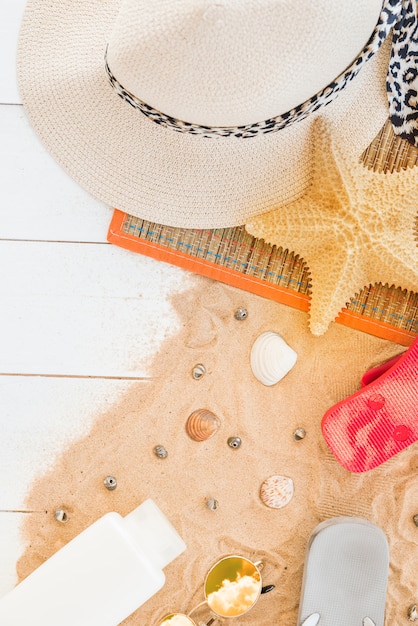 Kostenloses Foto matte mit hut und starfish in der nähe von muscheln und flasche auf sand