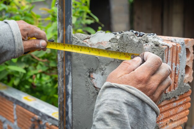 Maurerarbeiten. Bauarbeiter, der eine Backsteinmauer errichtet.