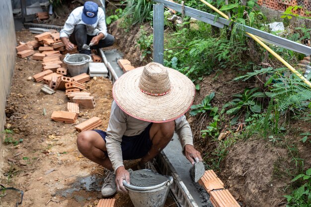 Maurerarbeiten. Bauarbeiter, der eine Backsteinmauer errichtet.