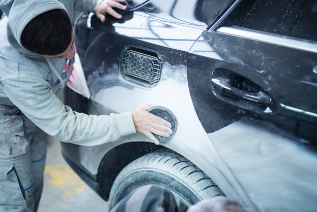Mechaniker Arbeiter Reparaturmann Schleifen Polieren Karosserie und Vorbereitung Auto für die Lackierung in Werkstatt Garage
