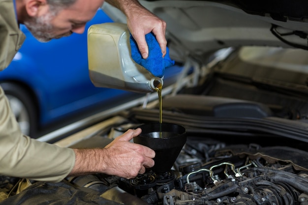 Mechaniker gießt Öl in Auto-Motor