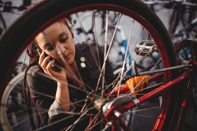 Mechaniker im Gespräch über Handy während Fahrrad reparieren