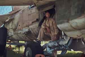 Kostenloses Foto mechaniker in uniform und flughelm führt wartung eines alten militärbombers im freilichtmuseum durch.