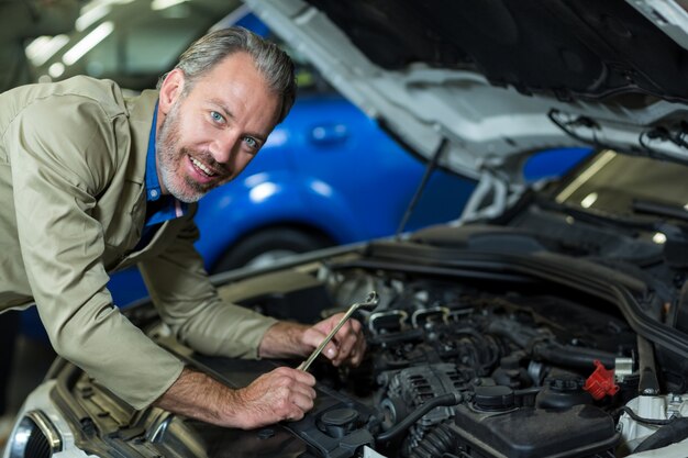 Mechaniker lächelnd, während ein Auto Motor gewartet