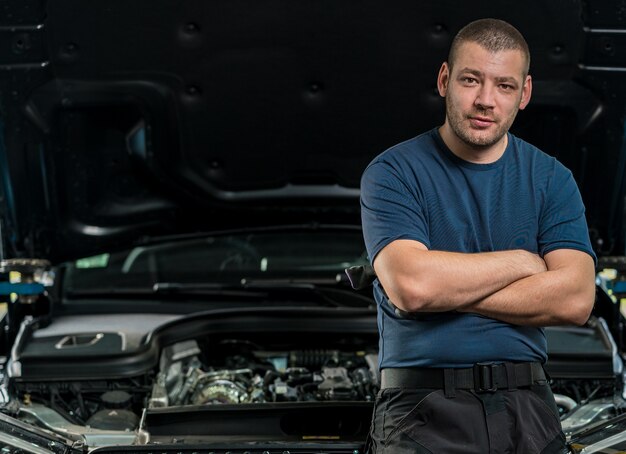 Mechaniker lehnt sich an die Motorhaube eines Autos