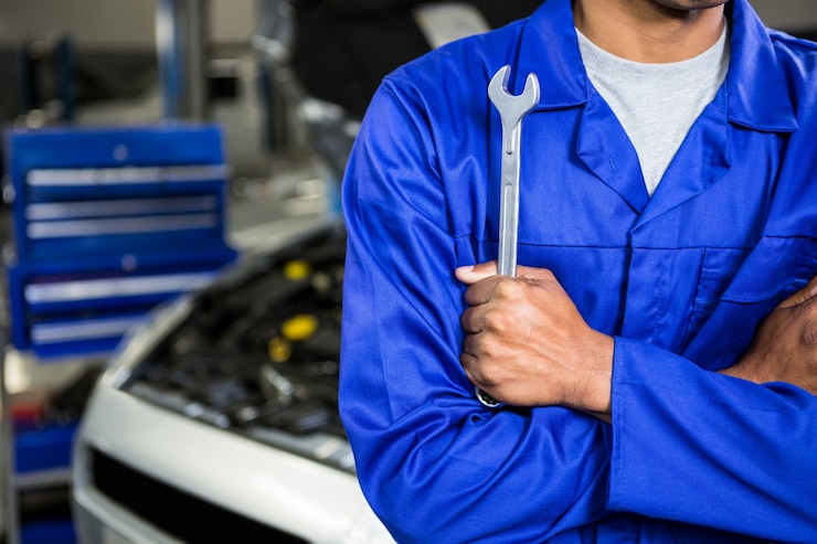 Kostenlose Foto mechaniker mit gekreuzten armen hält einen schlüssel